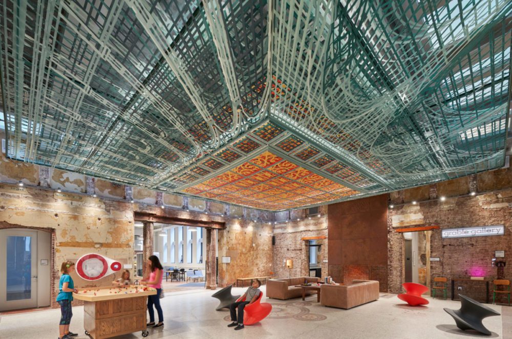 entry room of historic building with unique ceiling installation of layered laser cut fabric mimicking former skylight design