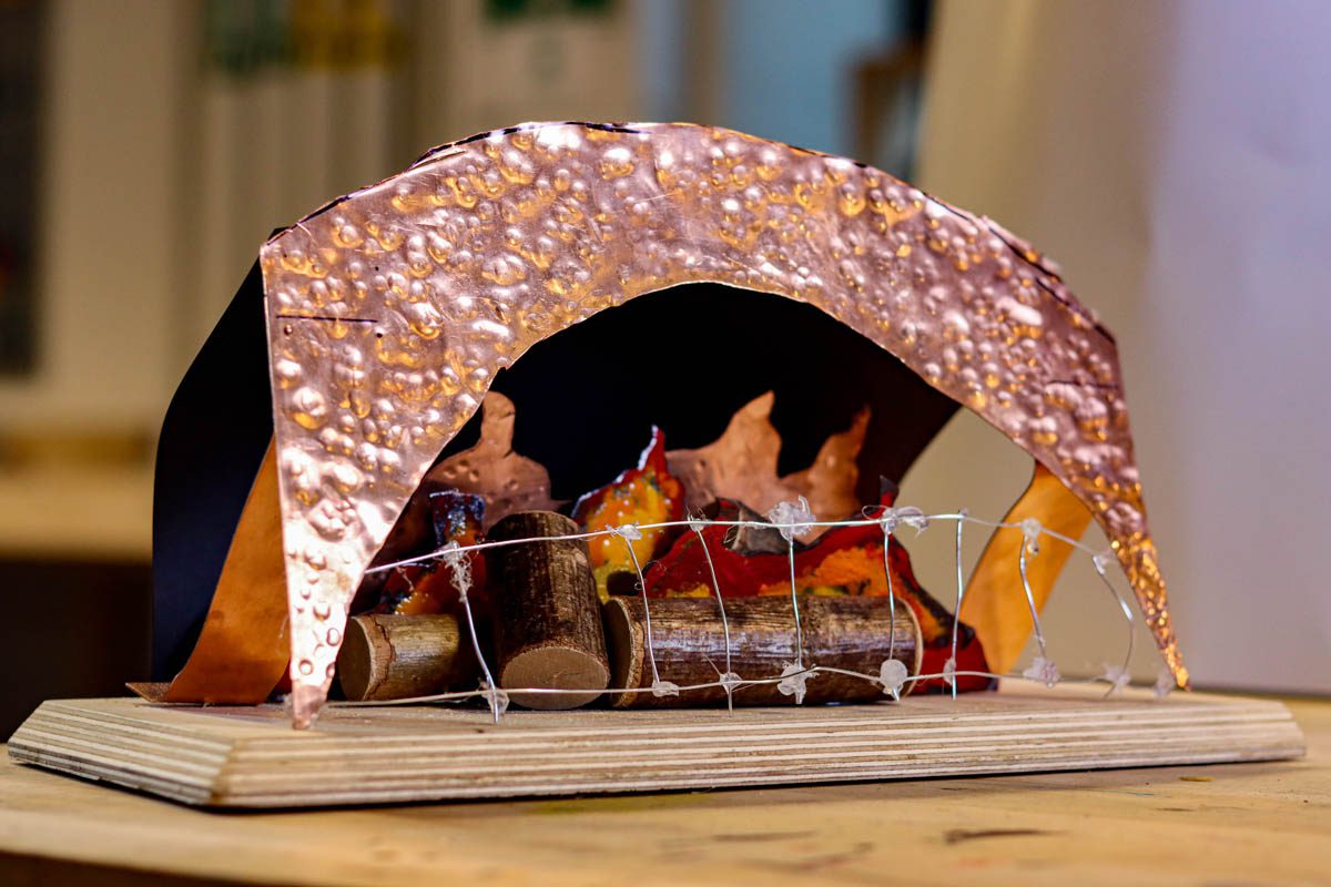 metal sculpture of campfire and tent in copper