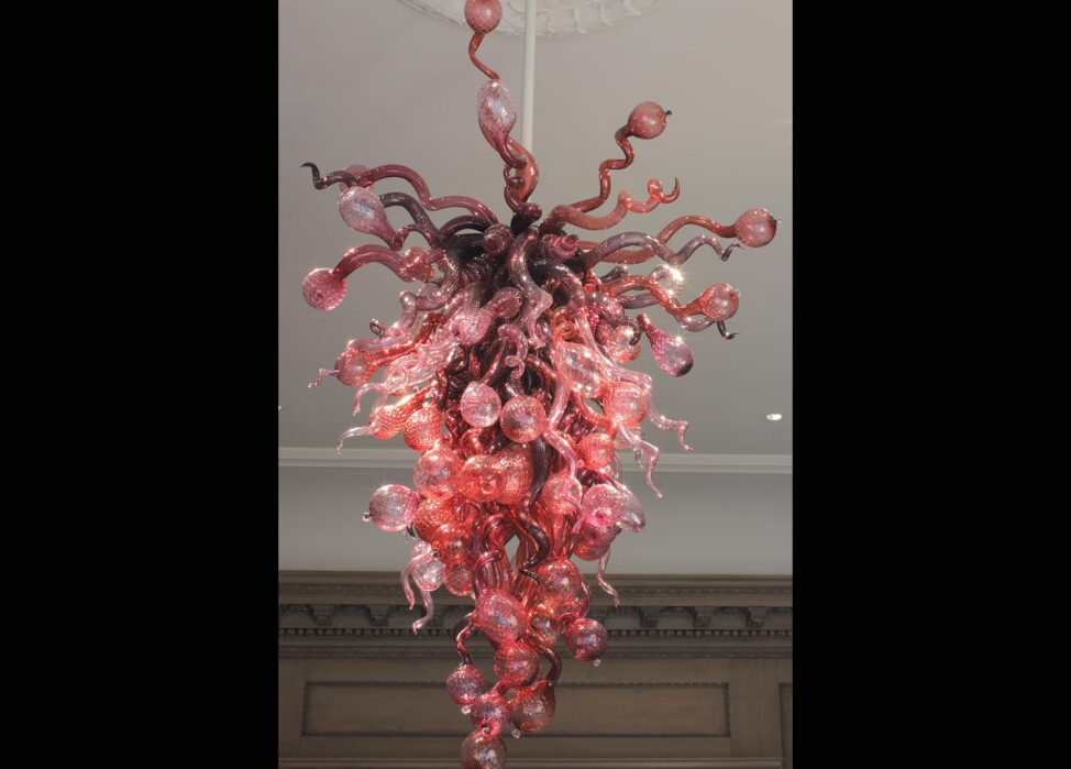 a pink, hanging glass sculpture made of twisted lengths joined into the shape of a hanging fixture